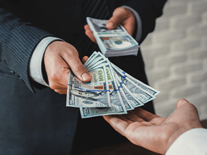 Two individuals exchanging cash, symbolizing a collateral loan or merchant cash advance transaction.