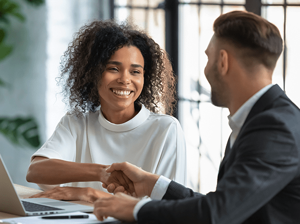 A smiling woman shaking hands with a professional lender during a secure collateral loan consultation at Qollateral.