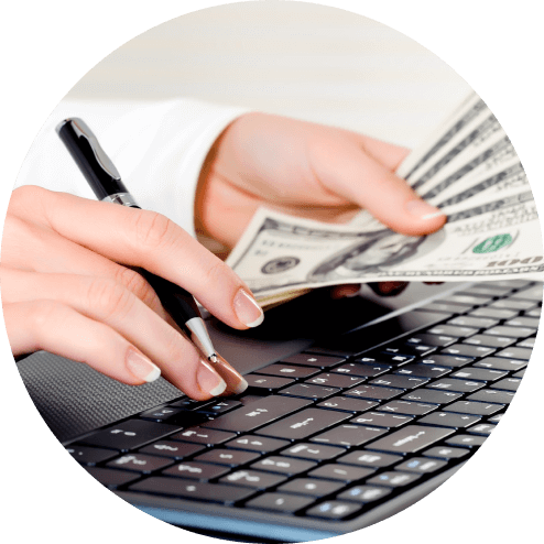 Hands holding cash over keyboard during online loan application for luxury assets.