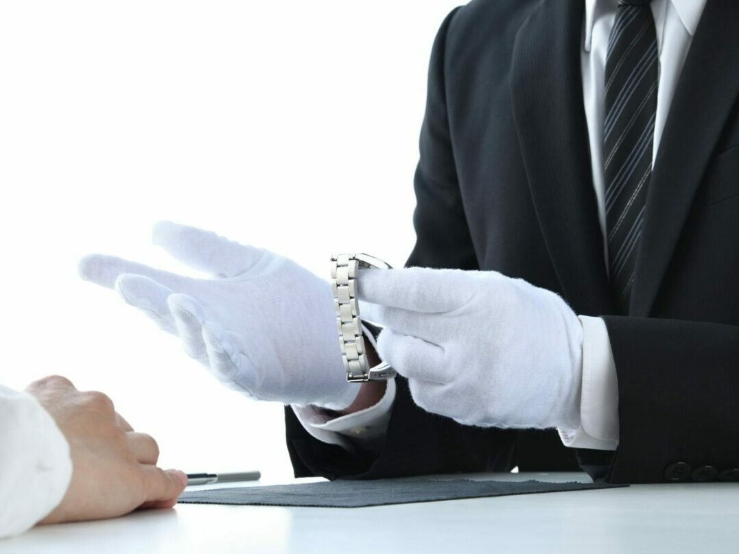 Luxury watch appraisal being conducted by a professional wearing white gloves.
