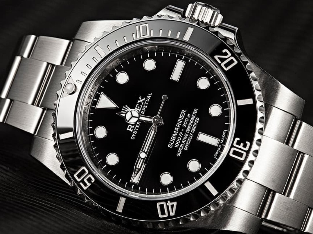Close-up of a Rolex Submariner watch with a stainless steel band and black dial, showcasing its timeless design and investment potential.