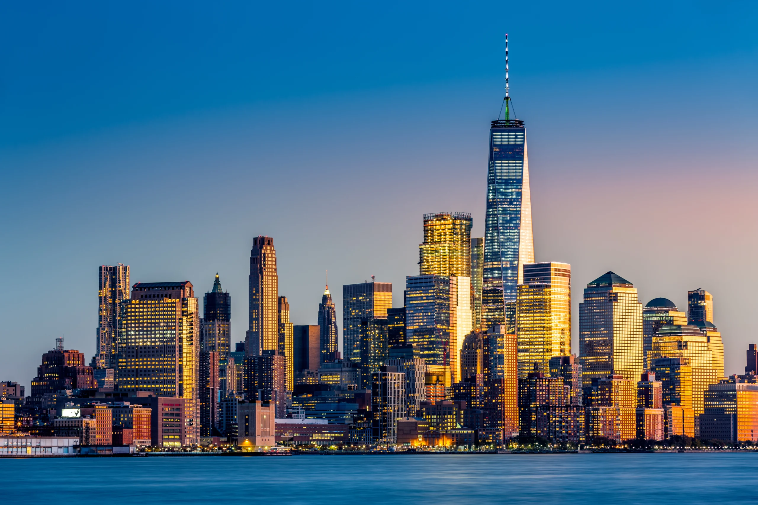 Manhattan skyline at sunset with One World Trade Center and glowing city lights