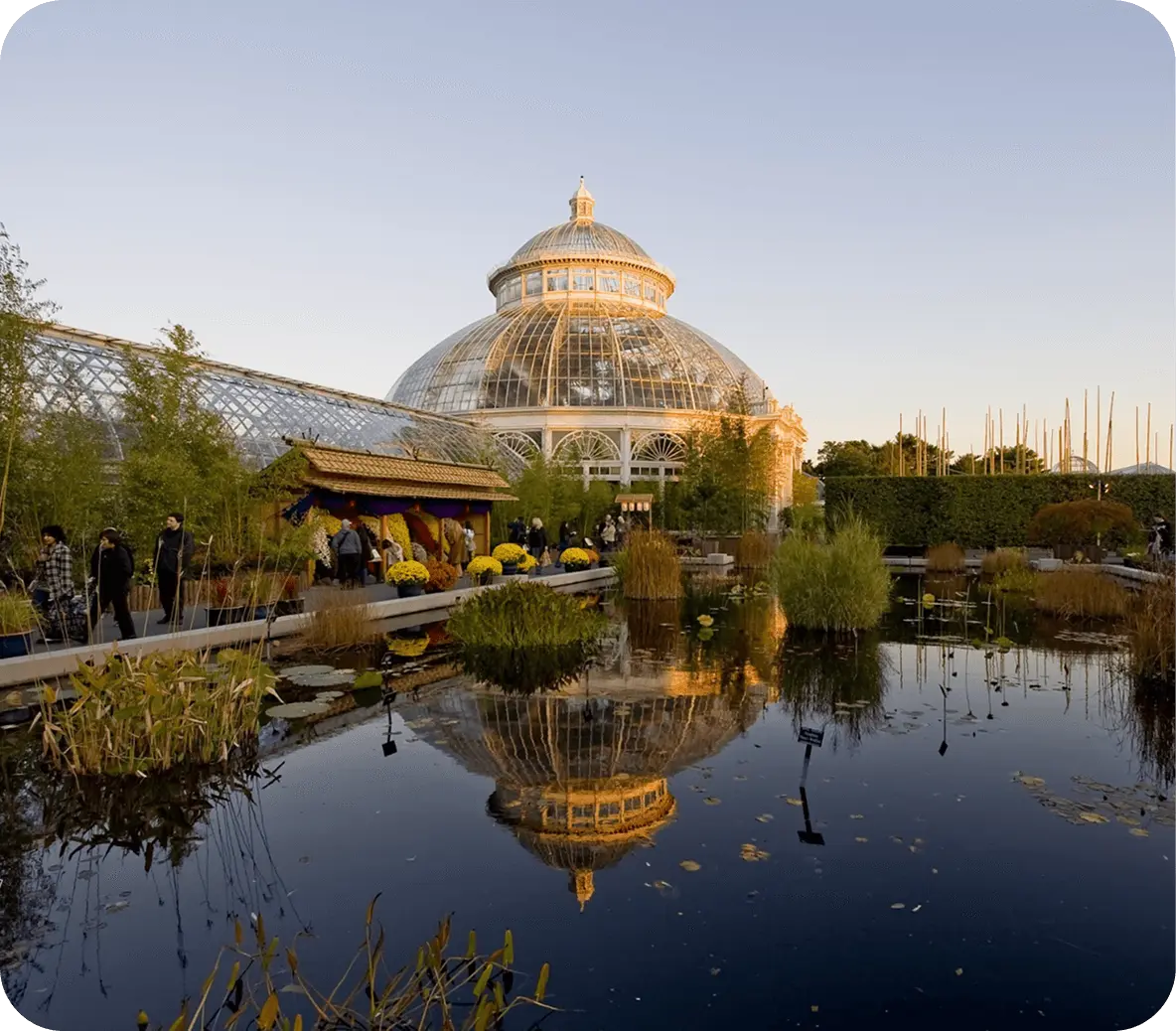 The Enid A. Haupt Conservatory at the New York Botanical Garden with a pond reflecting the glass-domed structure