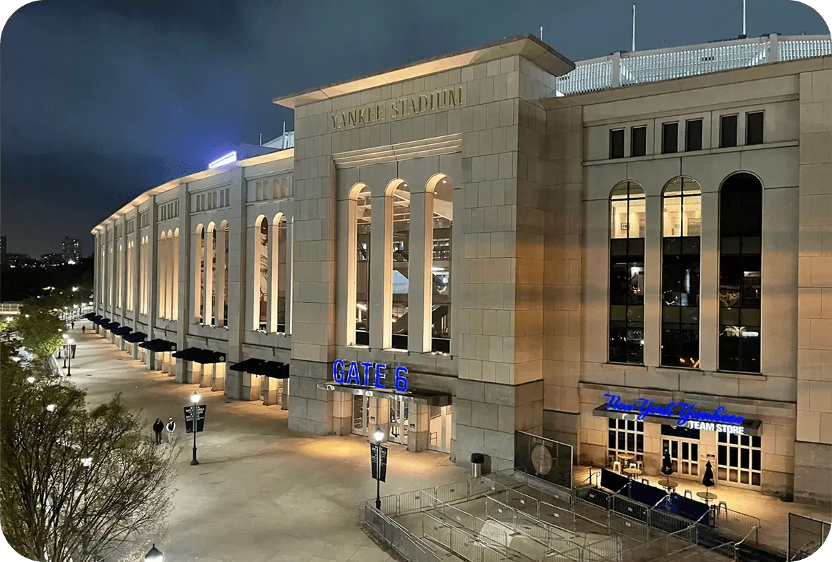Exterior view of Yankee Stadium at night with Gate 6 entrance and New York Yankees Team Store
