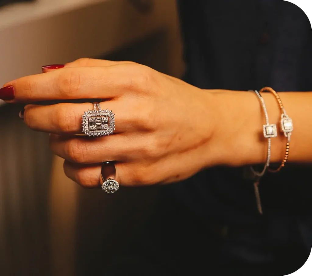 Woman’s hand adorned with multiple diamond rings and bracelets in a luxury setting