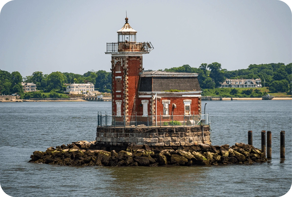 Small historic lighthouse on a rocky island surrounded by water