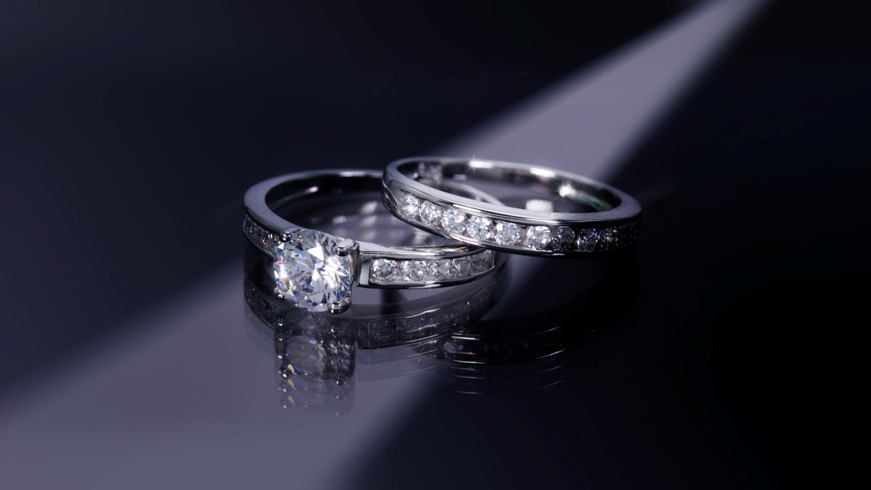 Two diamond engagement rings displayed under dramatic lighting, symbolizing luxury jewelry sales and appraisals at Qollateral.