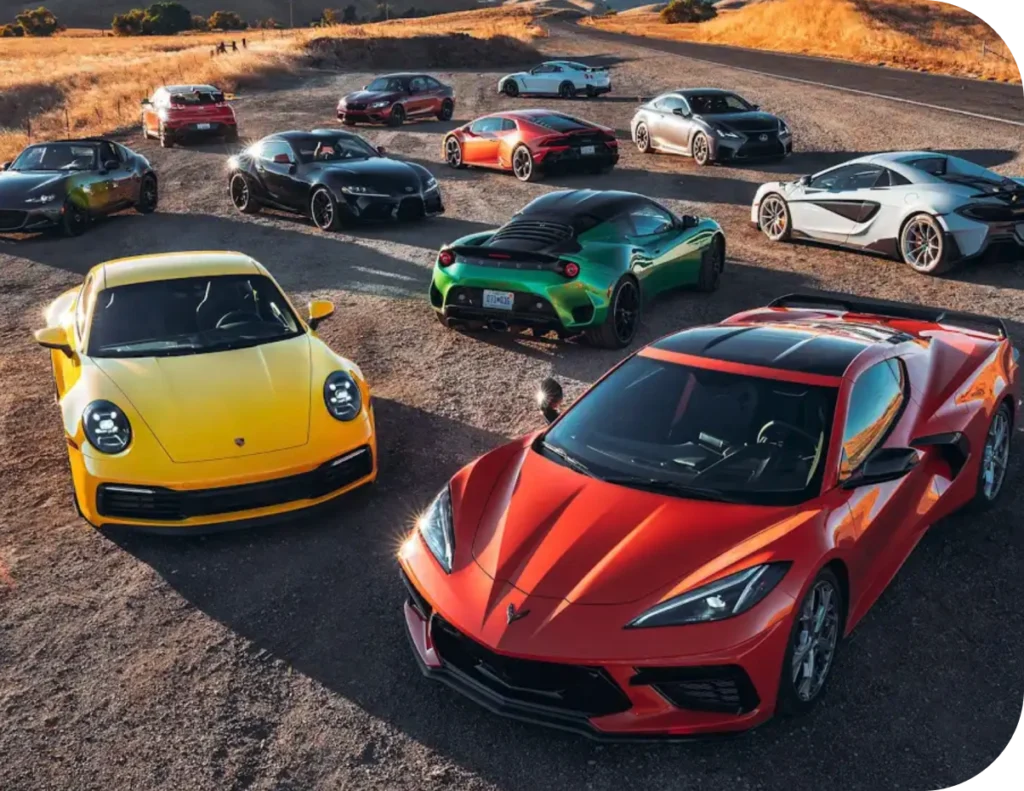 Group of sports cars and supercars including a Corvette C8, Porsche 911, and McLaren parked together outdoors